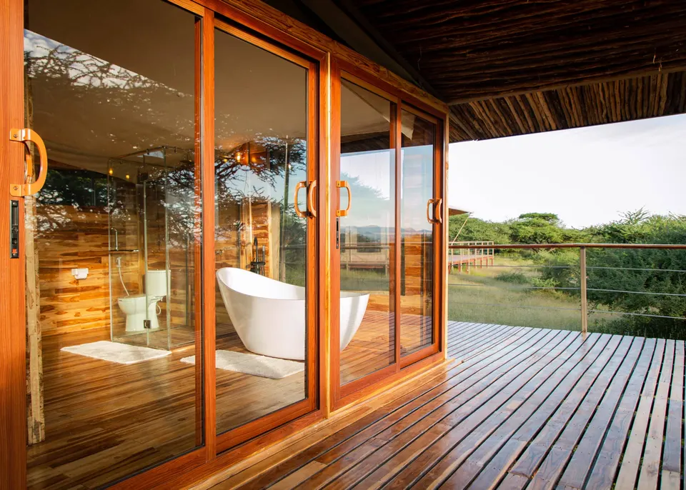 Naserian glazed bathroom opening to a deck, with freestanding bath visible