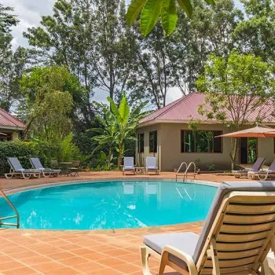 Swimming pool, loungers and chalet buildings at Arusha Planet Lodge