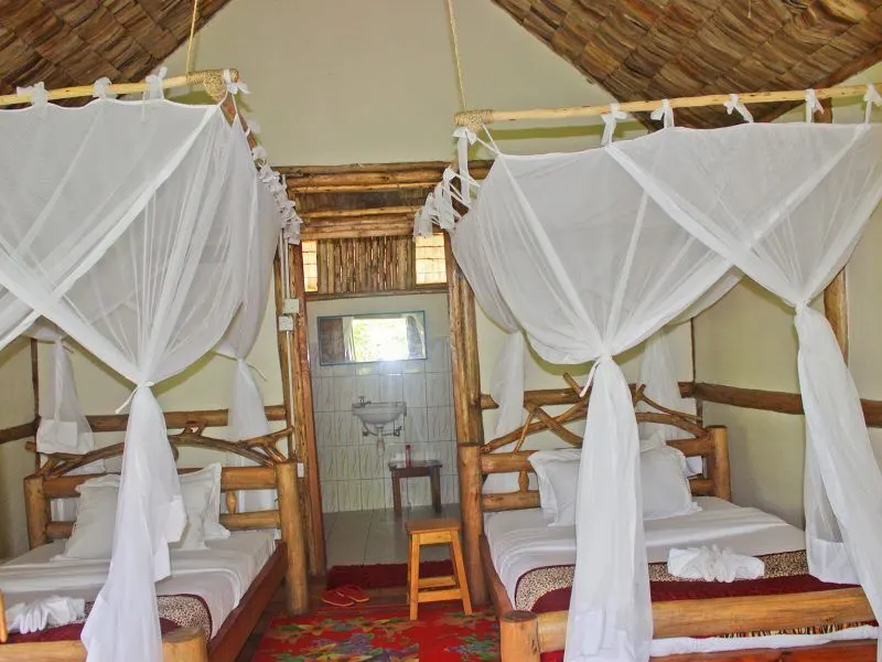 Twin beds with mosquito nets in a thatched room