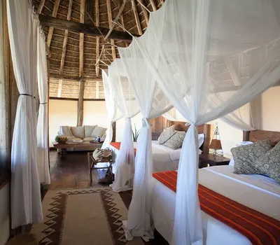 Apoka chalet bedroom with netted bed and indoor seating; public inline preview