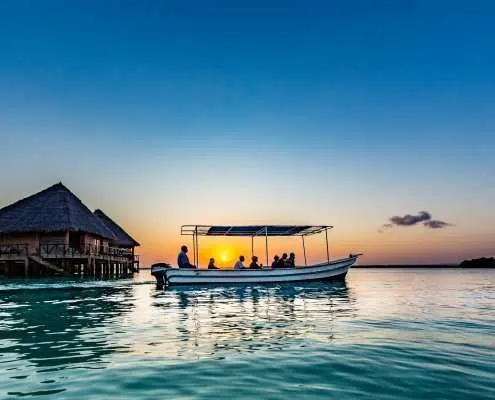 Chale Island boat beside overwater buildings at sunset