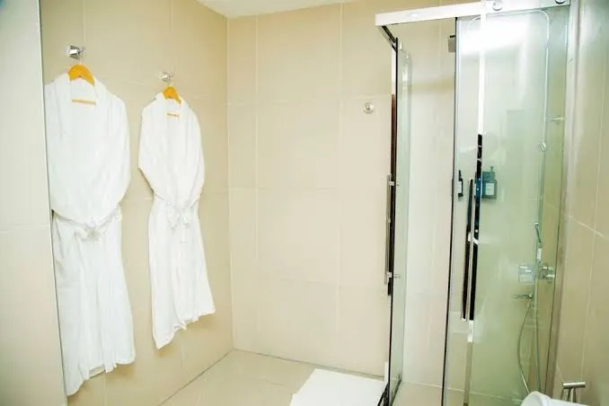 Bathroom with shower and hanging robes at New Amaan