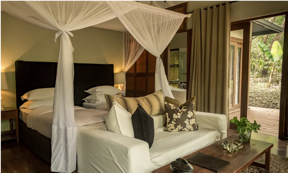 Chalet sitting area and canopy bed at Lake Duluti Lodge